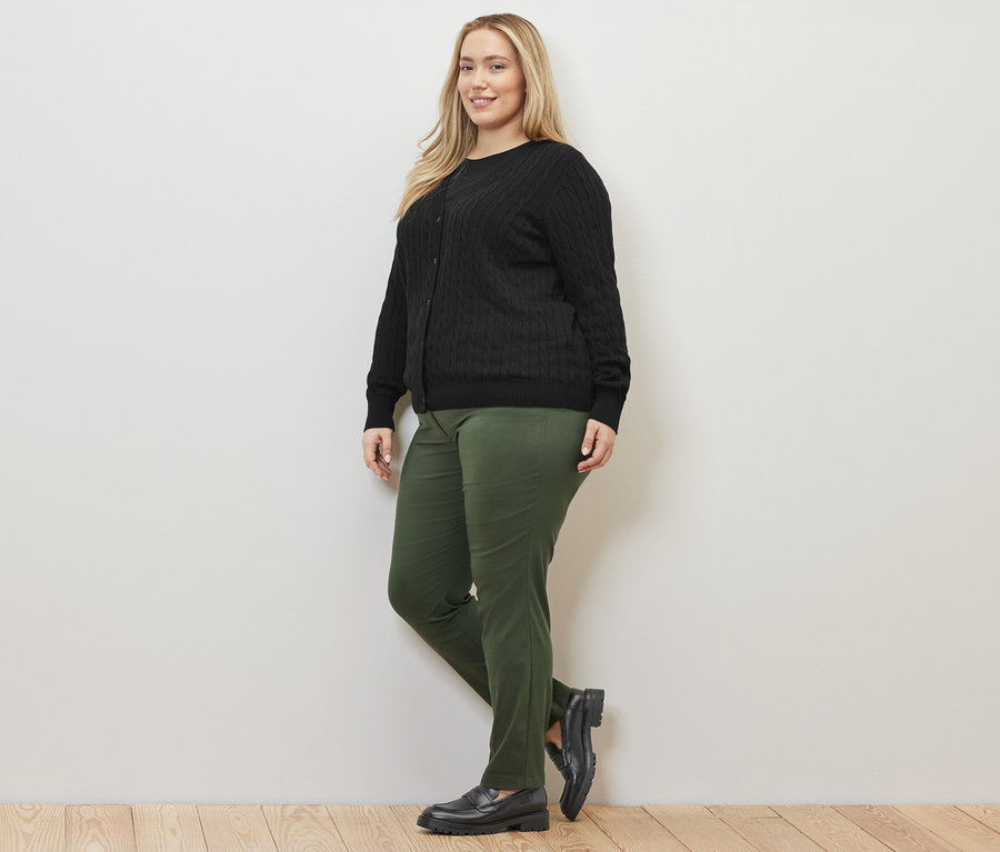 Kadın siyah Saç Örgüsü Motifli İnce Örgü Hırka ve yeşil Bengalin Pantolon ile poz veriyor.