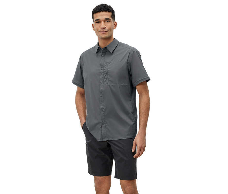 Adam gri outdoor gömlek ve siyah şortla poz veriyor.