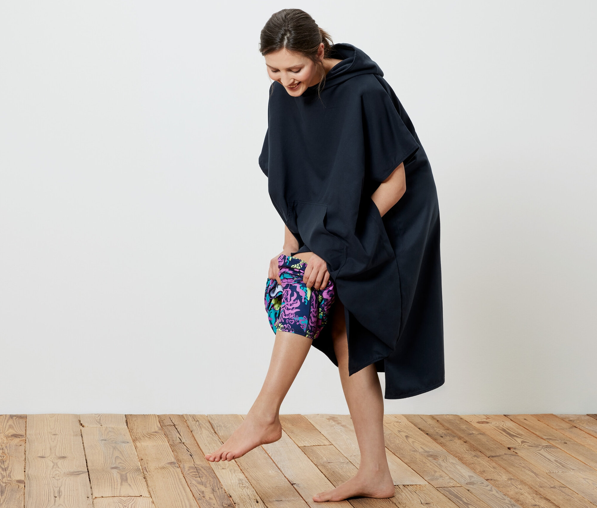 Gülümseyen bir kadın lacivert Üst Değiştirme Pançosu giyiyor.