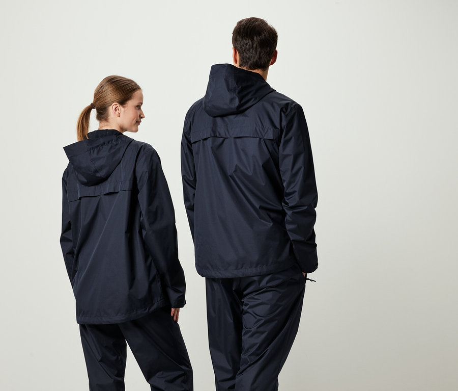 İki kişi kameraya arkaları dönük, üzerlerinde uyumlu lacivert kapüşonlu ceket ve pantolonlar var.