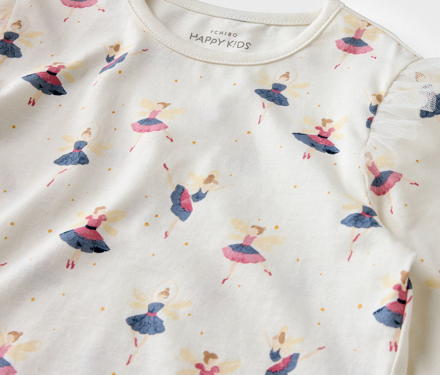 Balerin baskılı ve altın rengi noktalı beyaz bir tişörtün yakın çekimi.