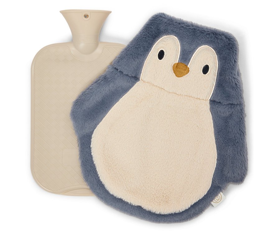 Bej renkli sıcak su torbası, penguen şeklinde peluş sıcak su torbası kılıfının yanında duruyor.