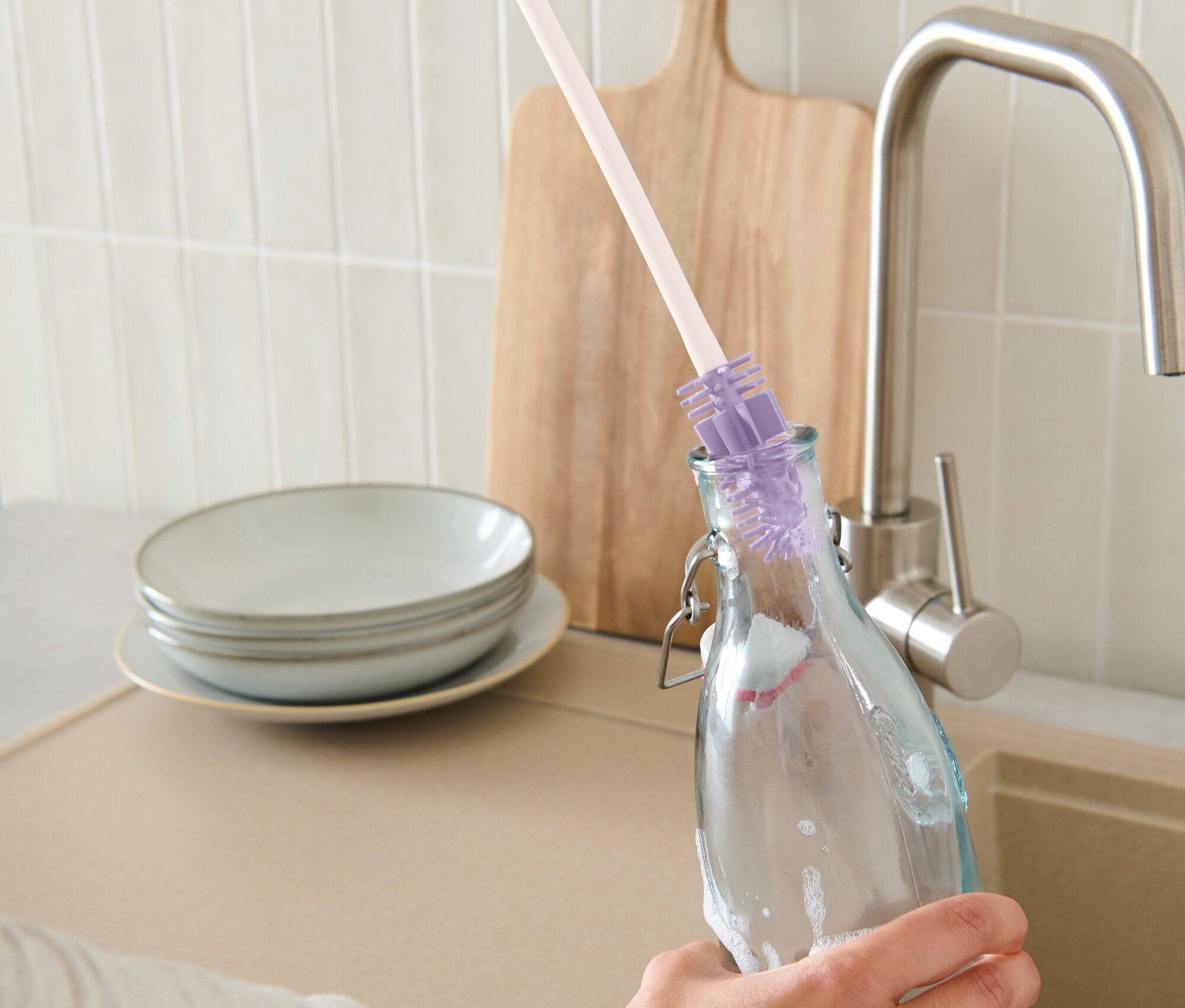 Bir el, bir şişe fırçasıyla şişe temizliyor.