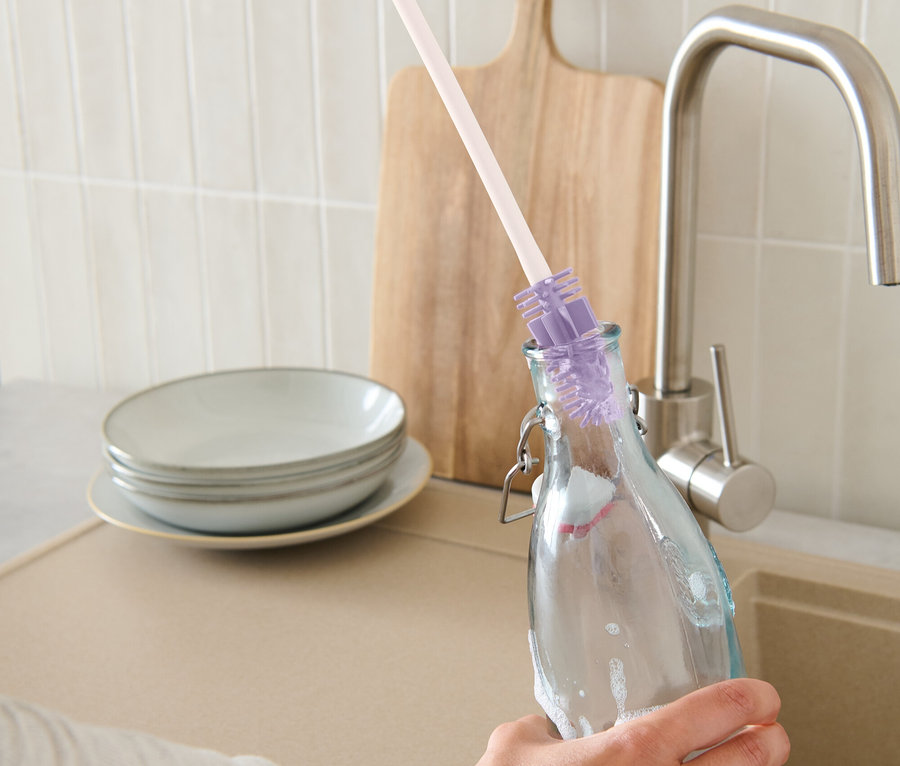 Bir el, bir şişe fırçasıyla şişe temizliyor.