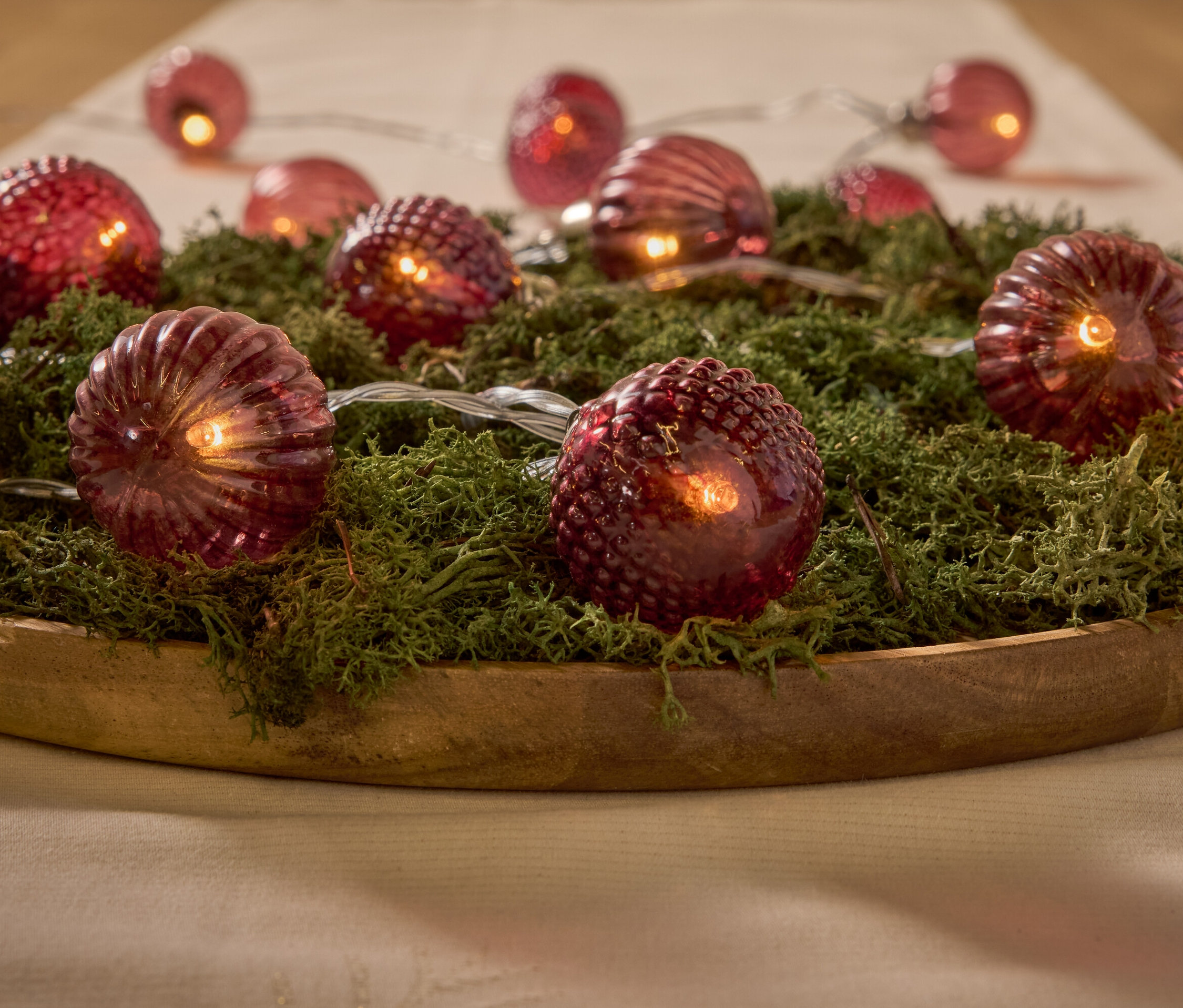 Ahşap bir kasede yosun üzerinde dekoratif kırmızı ışıklar.