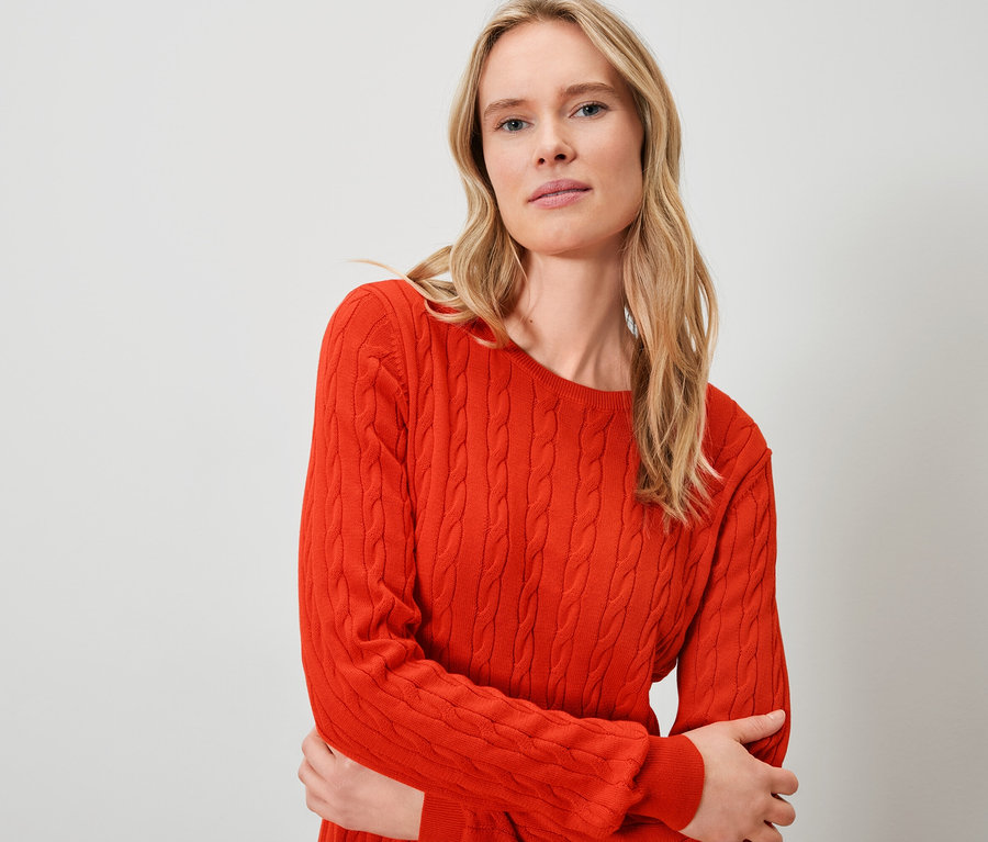 Sarışın bir kadın turuncu bir kazak giyiyor.