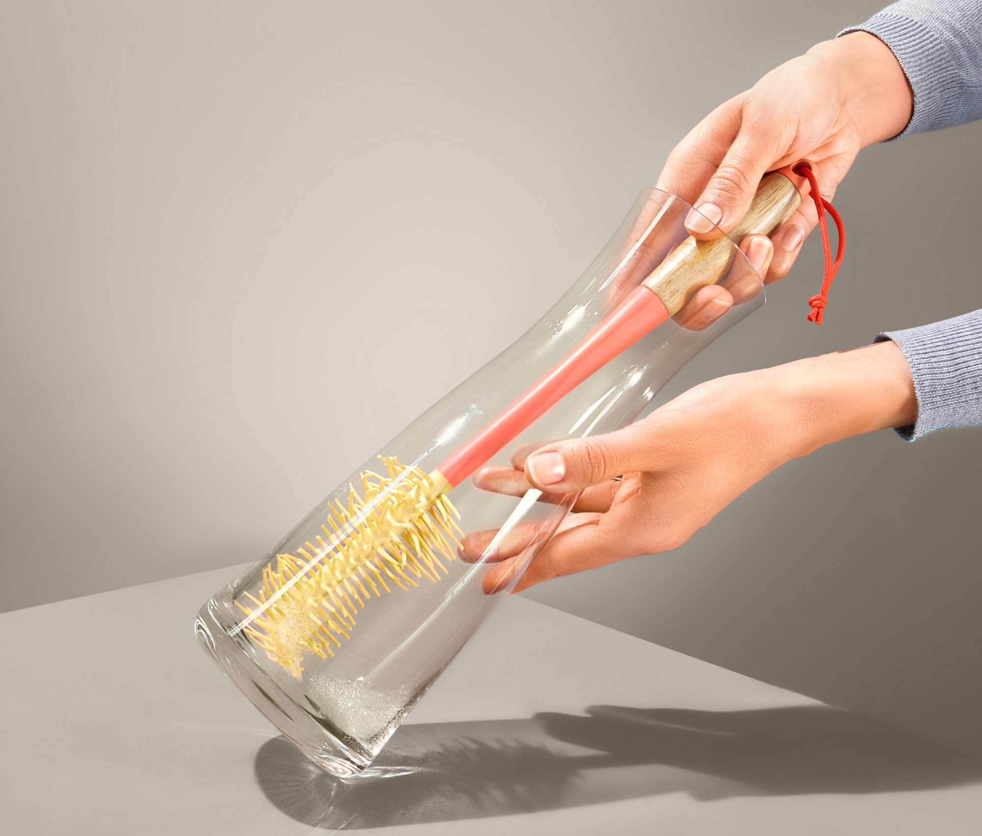 Kadın, Şişe Temizleme Fırçası ile cam vazoyu temizliyor.