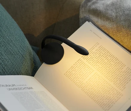 Siyah LED okuma lambası, koltuktaki açık bir kitaba takılıdır.