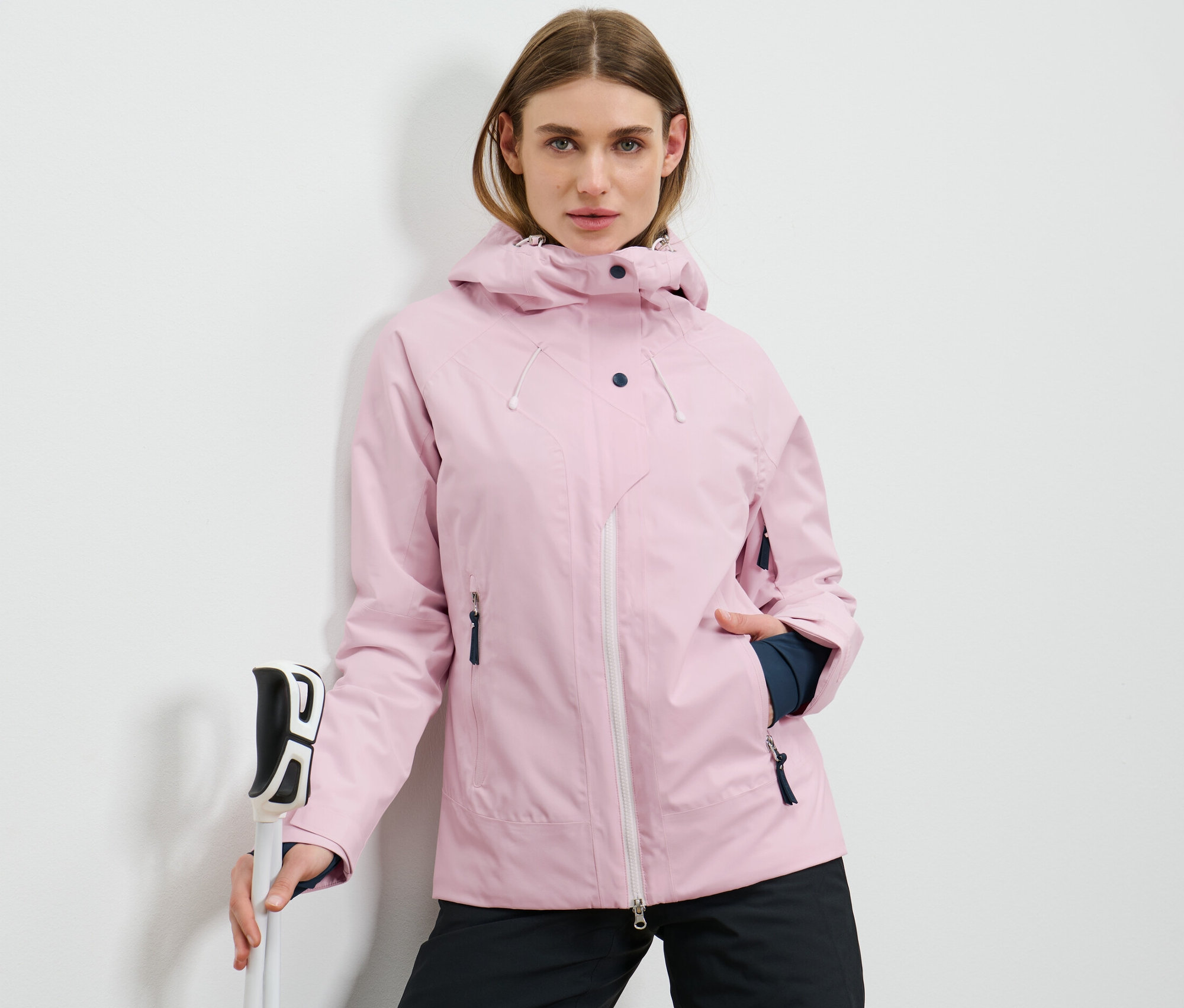 Kadın kayak batonları tutuyor ve pembe bir kayak montu giyiyor.