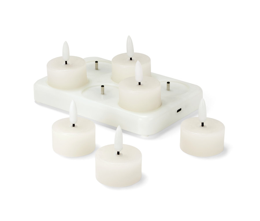 Altı adet LED'li, şarj edilebilir gerçek mumdan tealight, beyaz bir şarj istasyonunda duruyor.