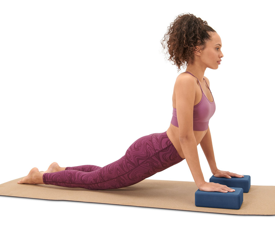 Kadın Yoga Seti'nden iki mavi yoga bloğu ile bir yoga matı üzerinde yoga yapıyor.