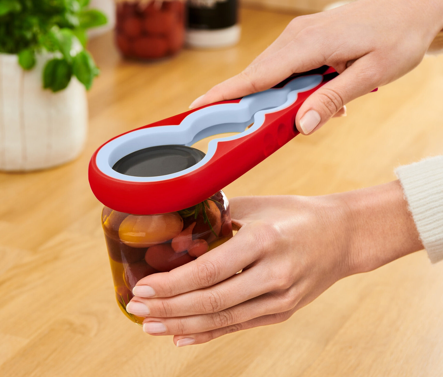 Bir kadın kırmızı bir kavanoz ve şişe açacağı ile bir kavanoz açıyor.