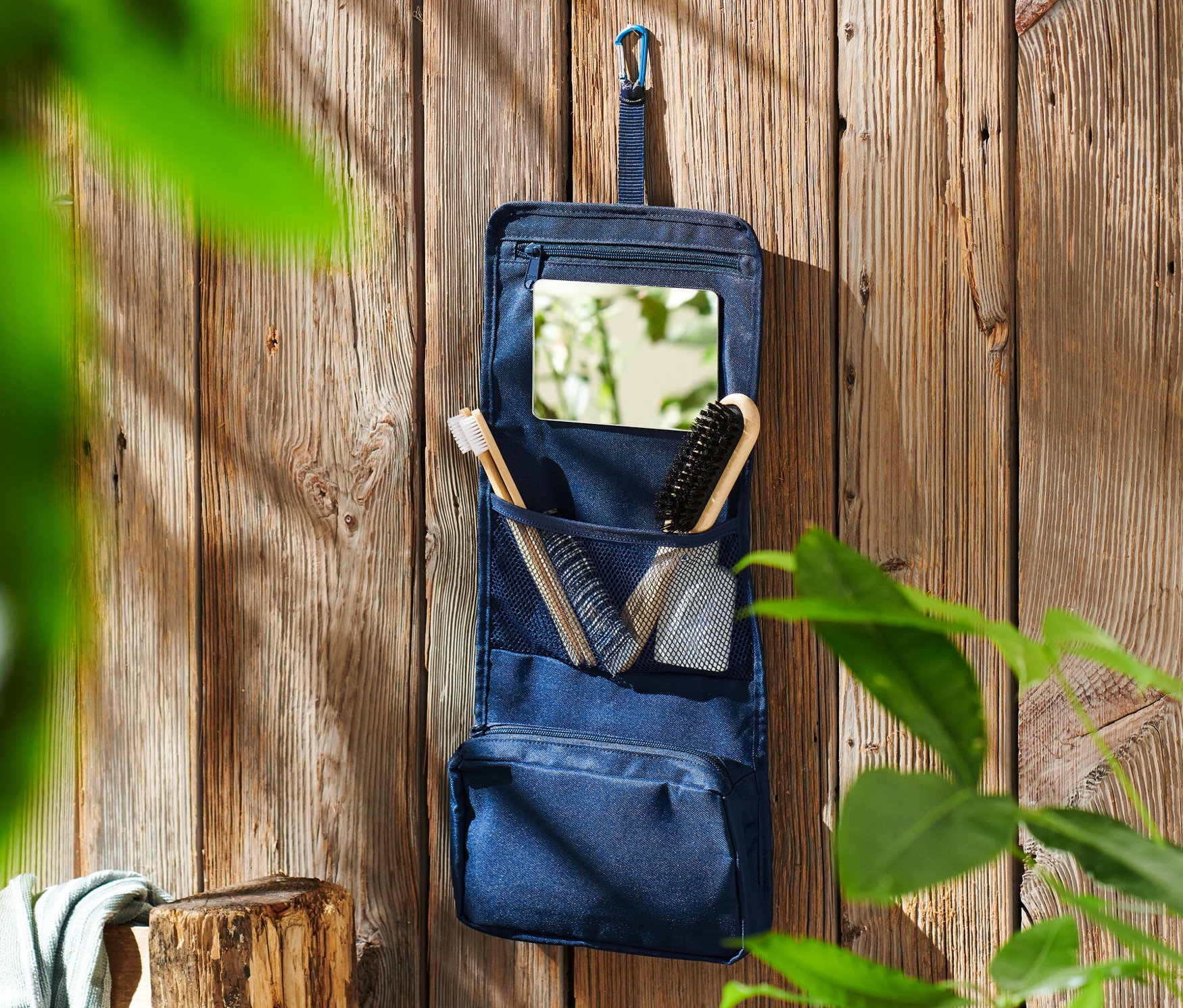 Mavi Kişisel Bakım Çantası ahşap duvara asılı duruyor.
