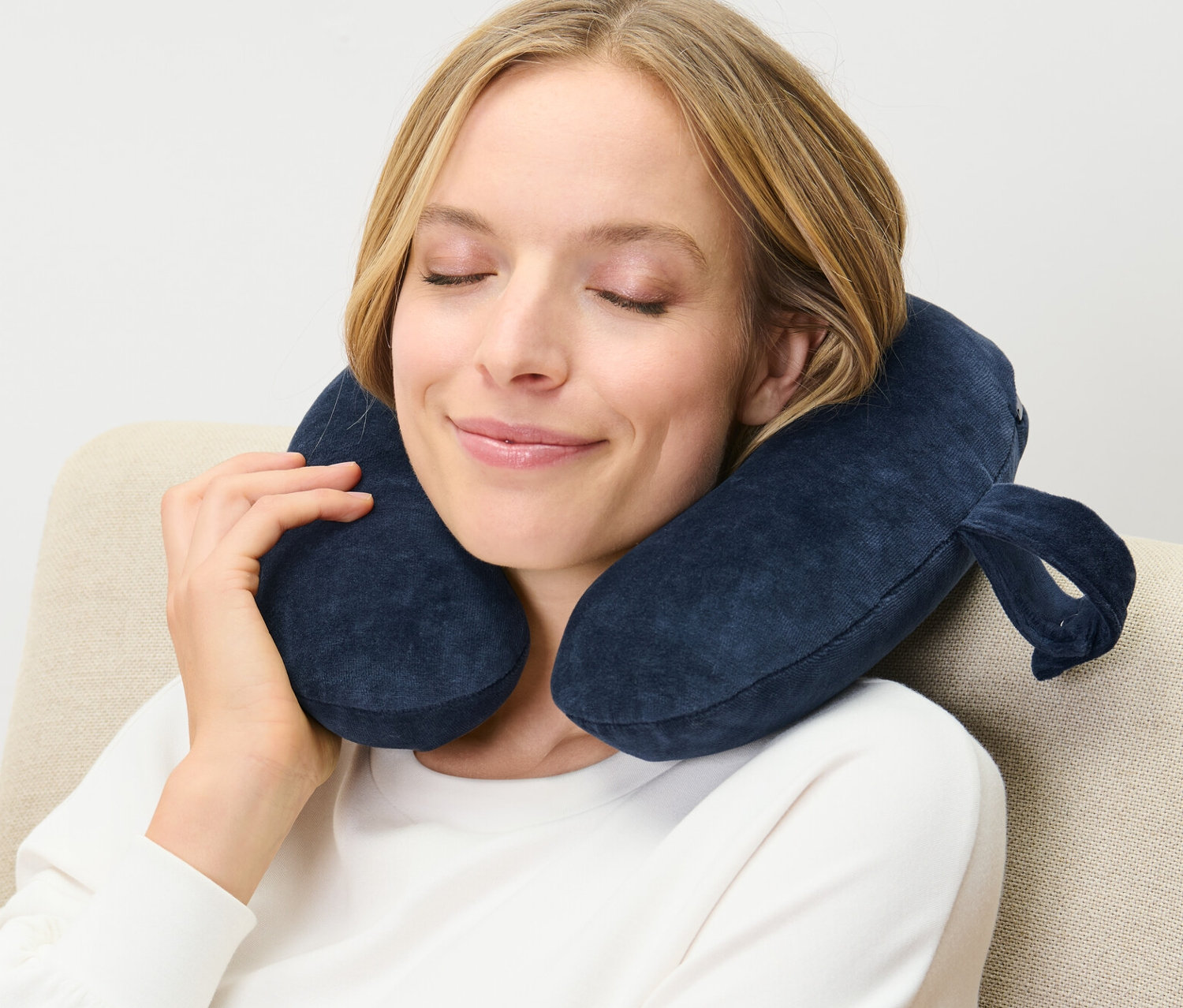 Kadın koltukta oturuyor, boynunda lacivert hafızalı süngerli boyun yastığı var.