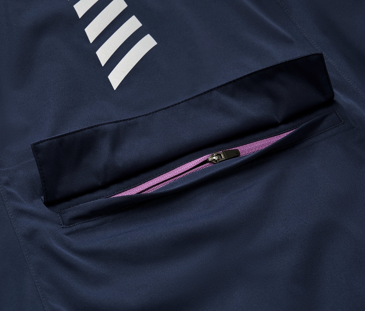 Beyaz şeritli ve mor fermuarlı lacivert bir Rad-Regenjacke detayı.
