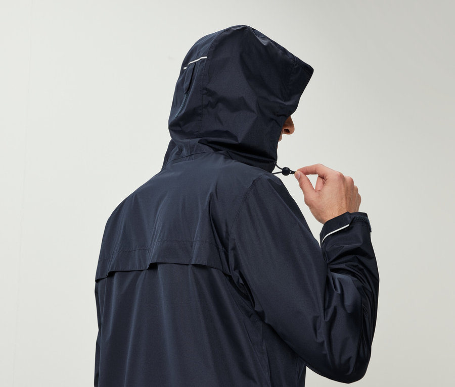 Kapüşonlu lacivert bir yağmurluk giyen bir adam kapüşonunun ipini çekiyor.