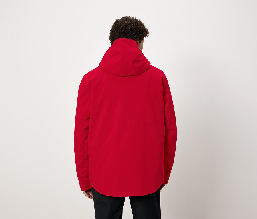 Arkası dönük bir adam, kırmızı kapüşonlu bir ceket giyiyor.