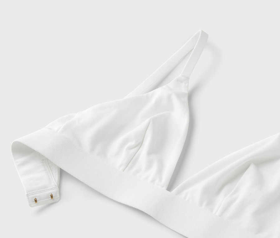 Beyaz bir arka plan üzerinde ince askılı beyaz bir sütyenin yakın çekimi.