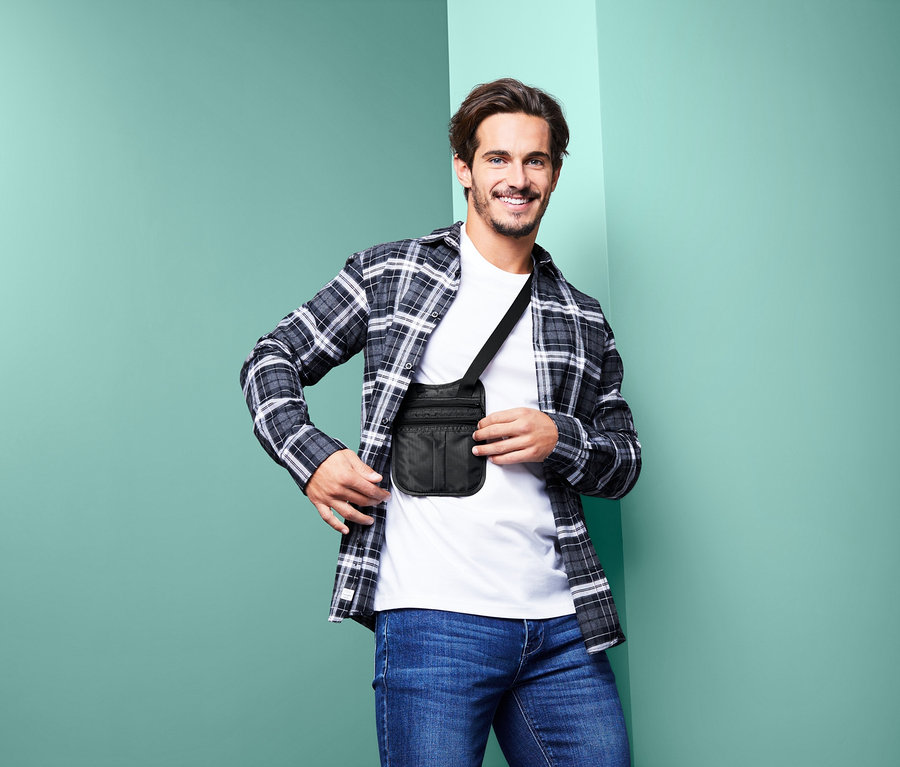 Gülümseyen bir adam, vücudunun üzerinde çapraz olarak siyah omuz kemerli güvenli bir çanta taşıyor.