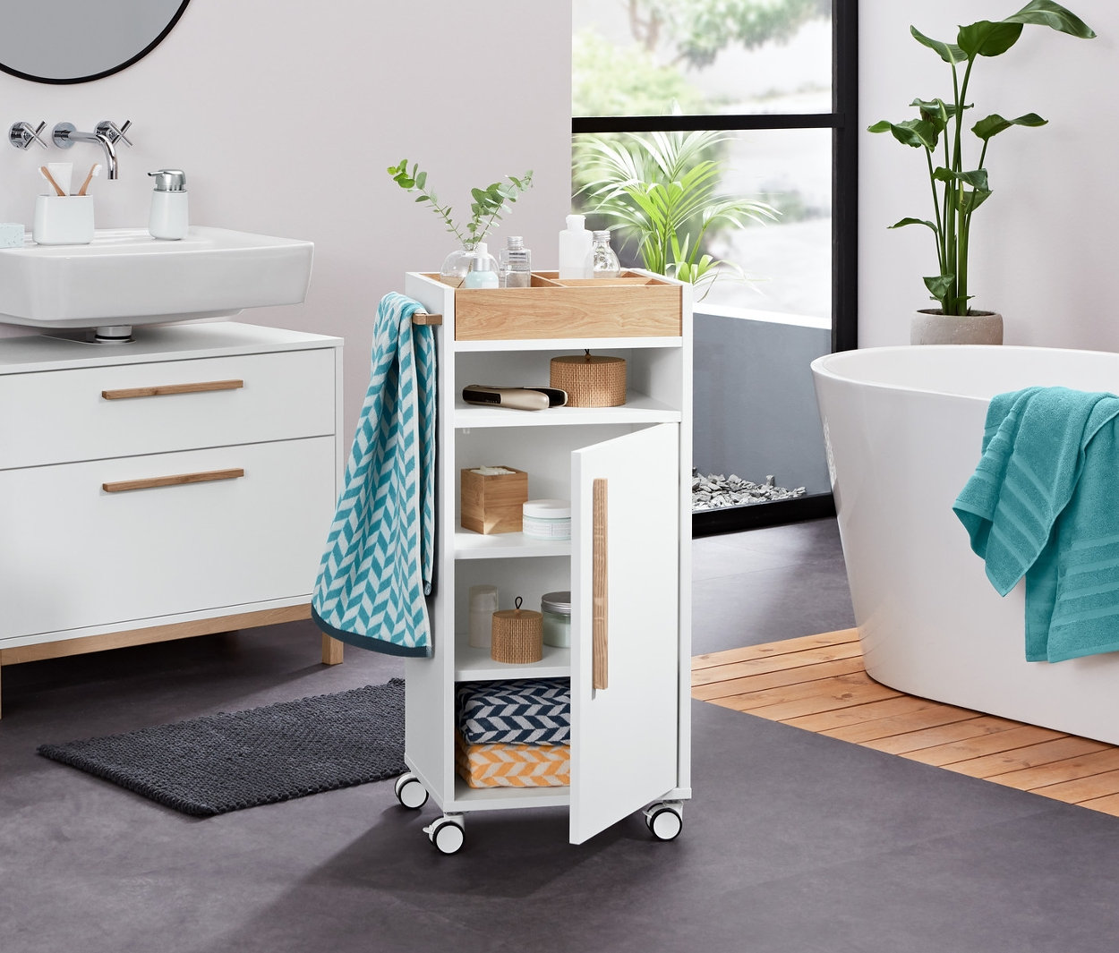 Banyoda beyaz »Eklund« 2 çekmeceli lavabo dolabı, sıvı sabunluk, banyo havlusu, jakarlı havlu, antrasit havlu, bambu kavanoz ve dekoratif LED taş bulunmaktadır.