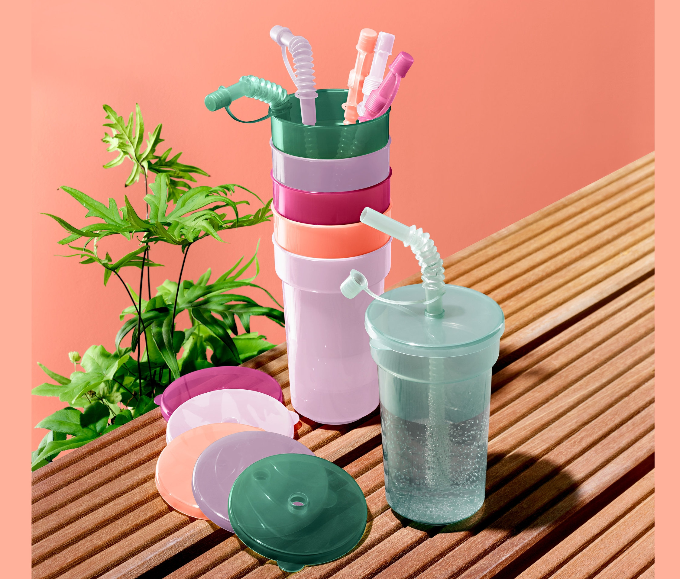 Çocuk bardağı seti kapakları ve pipetleriyle birlikte üst üste ve yan yana duruyor.