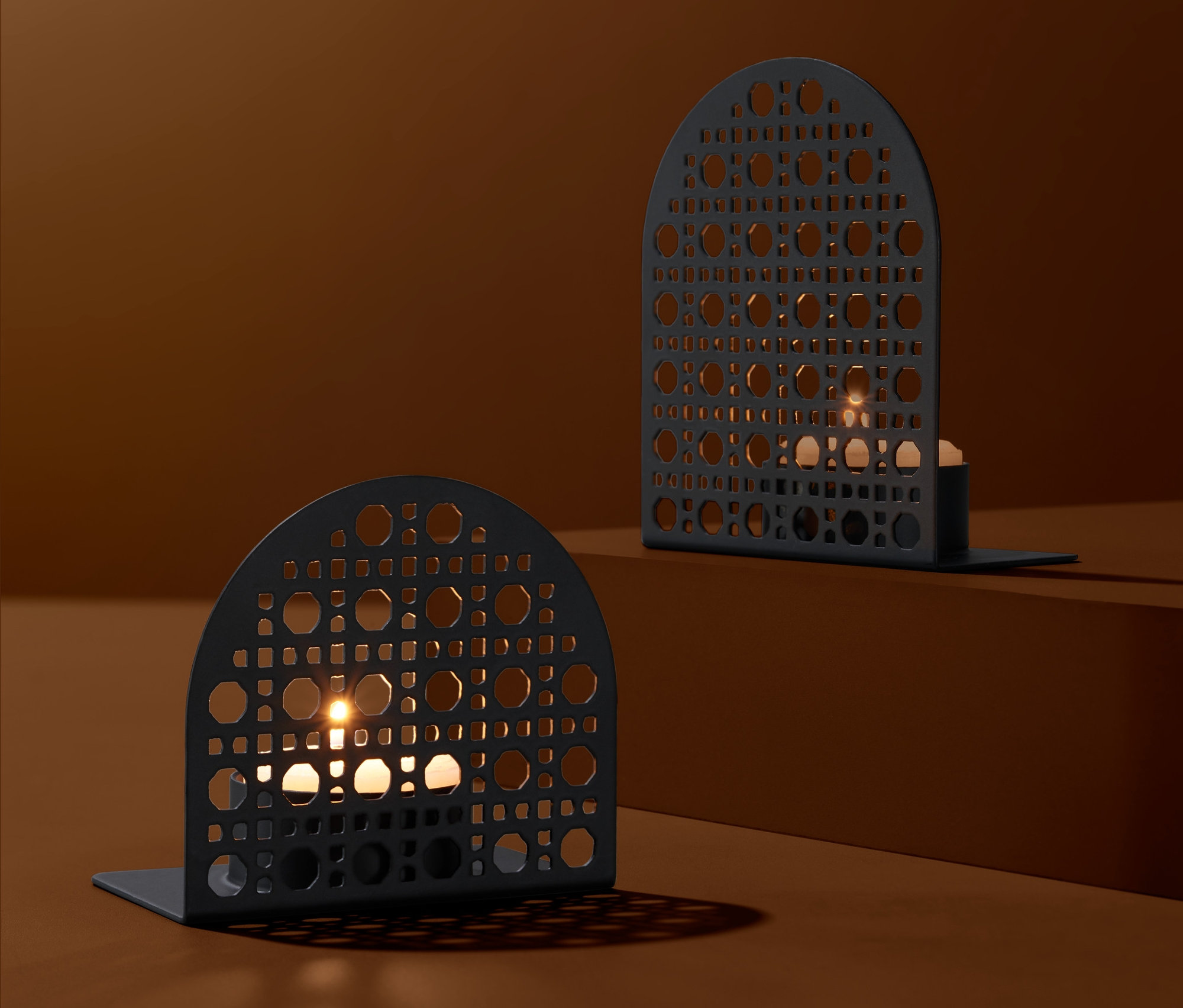 Geometrik desenli ve yanan mumları olan iki siyah tealight mumluk