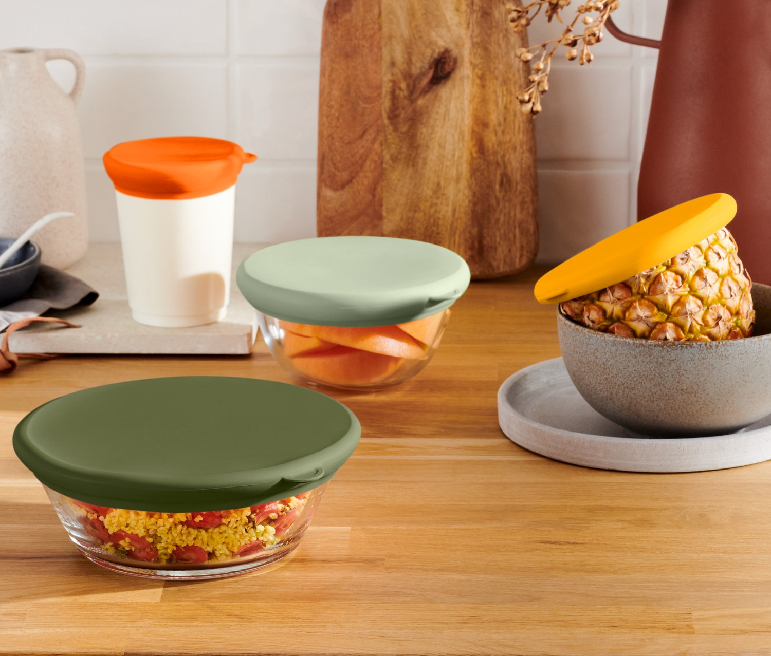 Dört adet renkli 4 Adet Taze Tutan Silikon Kapaklı cam kase ahşap bir yüzey üzerinde duruyor.