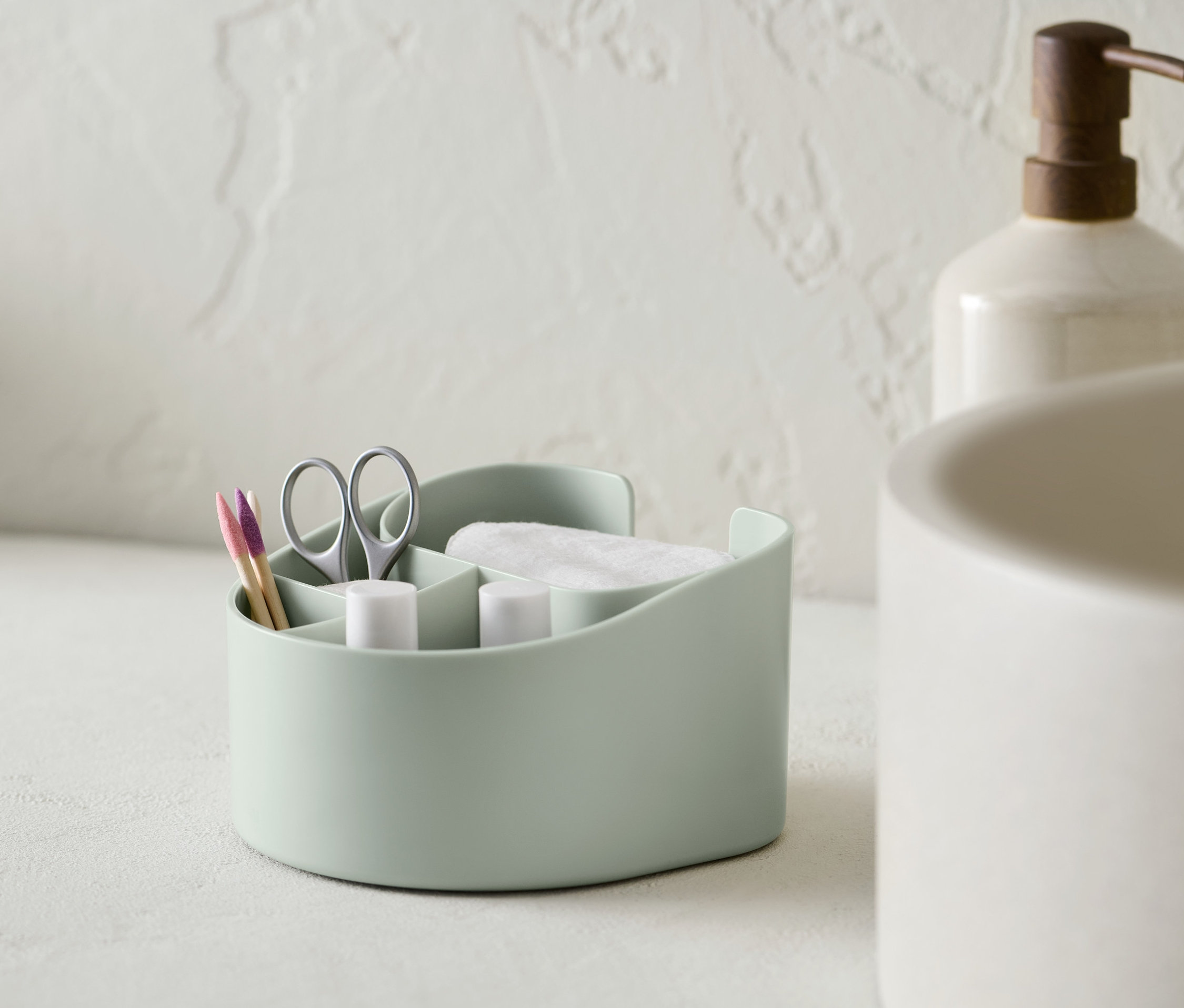 Pamuklu pedler, makas ve kulak çubukları olan açık yeşil bir kozmetik düzenleyici.