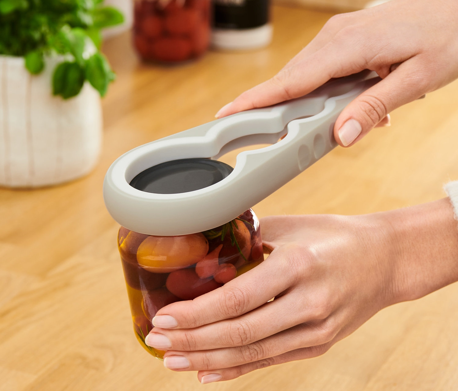 Kadın, Kavanoz ve Şişe Açacağı ile bir zeytin kavanozu açıyor.