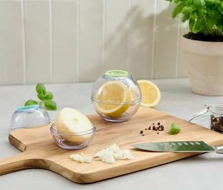 Bir limon ve bir soğan içeren iki adet Taze Tutan Küre, bir kesme tahtası üzerinde duruyor.