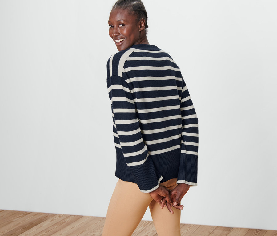 Kadın omzunun üzerinden bakıyor ve çizgili bir hırka giyiyor.