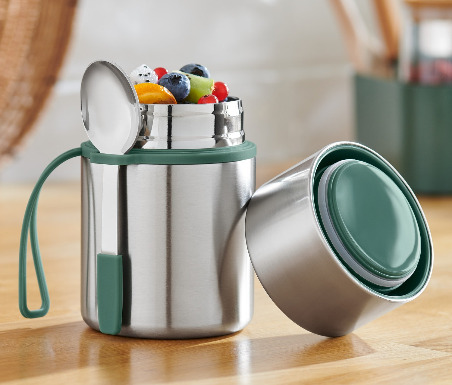 Açık bir Taşınabilir Termos Kap, içinde meyveler ve tahta bir masanın üzerinde bir kaşık bulunuyor.