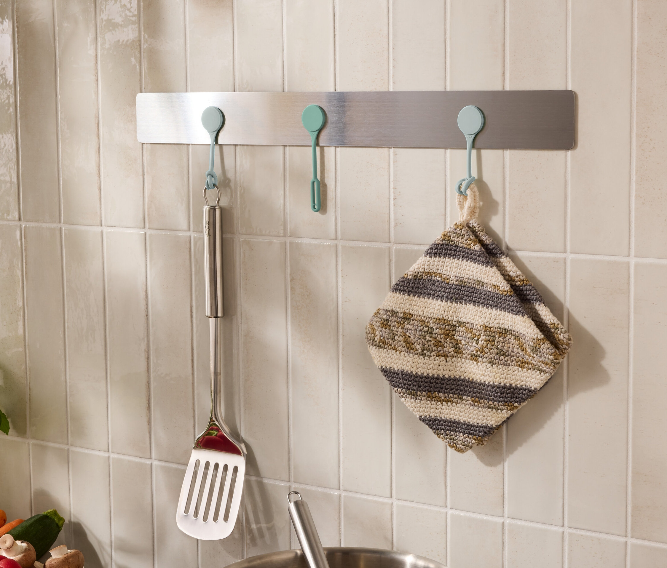 Duvarda kancalarda spatula ve bulaşık bezi gibi mutfak gereçleri asılıdır.