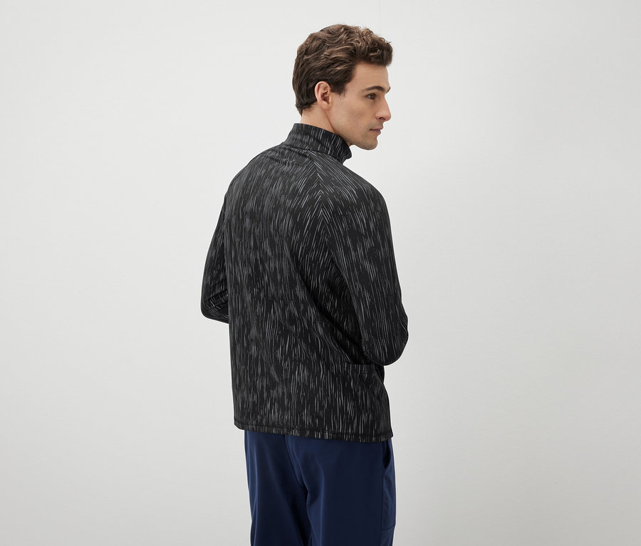 Adam sola bakıyor, siyah beyaz bir üst ve mavi pantolon giyiyor.