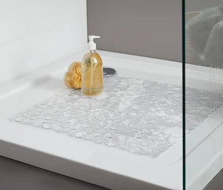 Şeffaf duş paspaslı duş teknesi. Küvette sarı bir banyo süngeri ve pompalı bir şişe var.