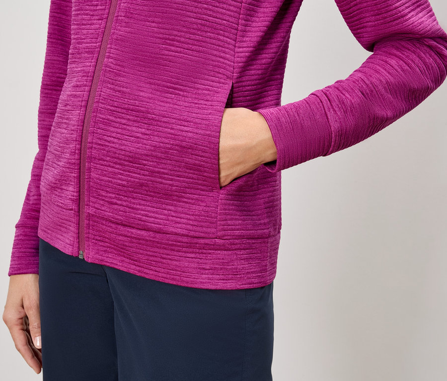 Pembe fermuarlı ceket ve lacivert pantolon giyen, elini ceket cebine sokan bir kişinin yakın çekimi.