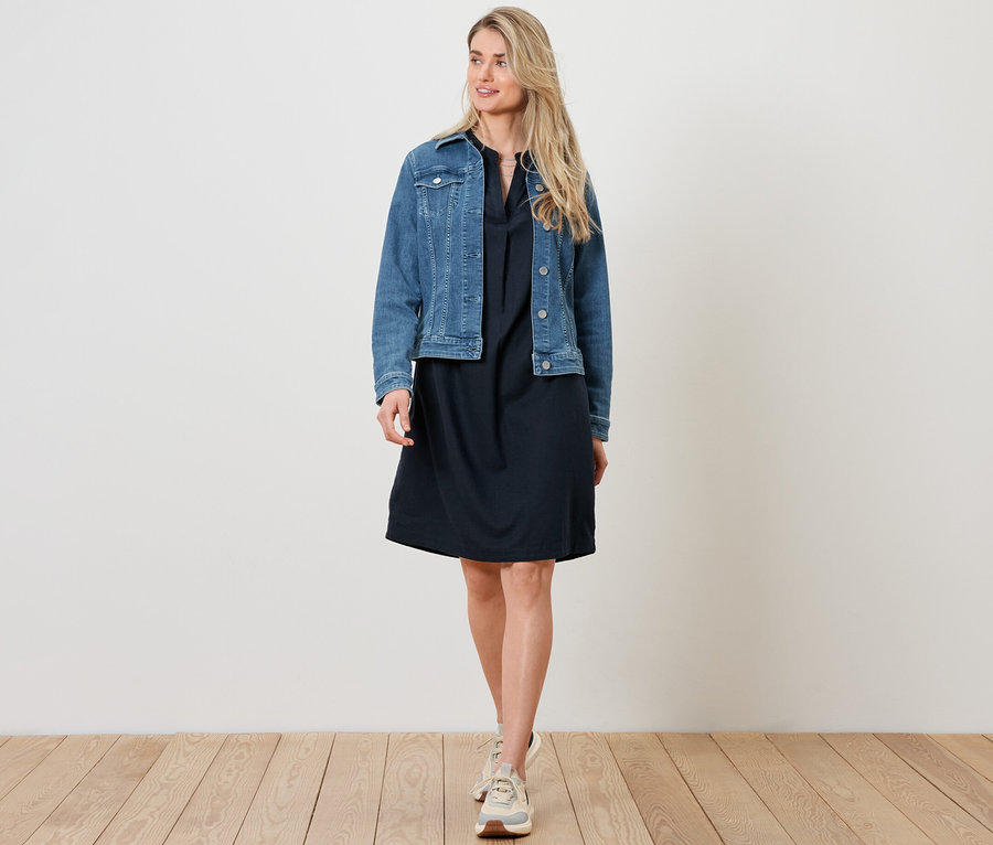 Kadın kot ceket ve keten elbise giyiyor.