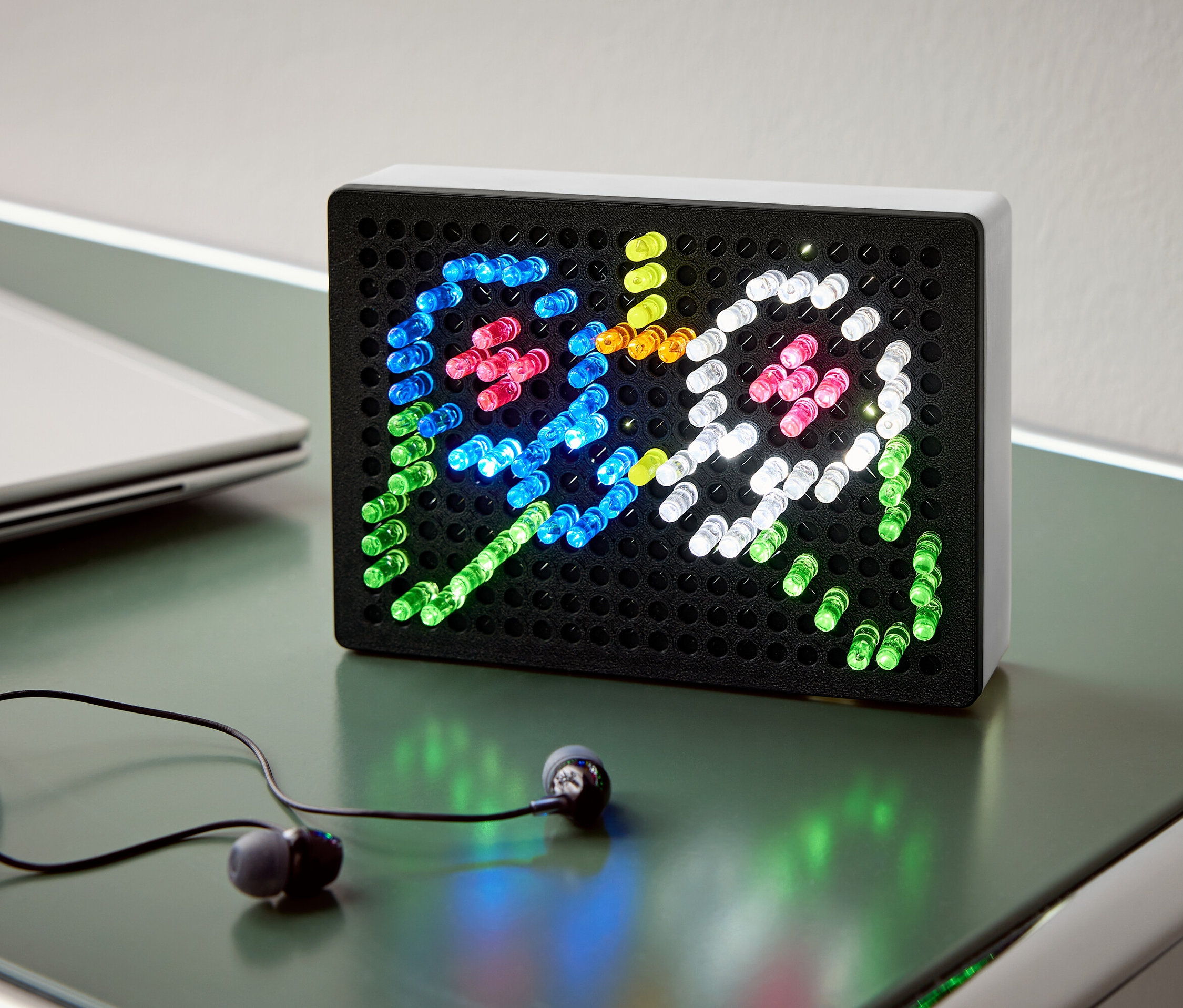 Masanın üzerinde iki hayaleti tasvir eden renkli ışıklı siyah bir ışık kutusu, yanında kulaklık ve bir not defteri duruyor.