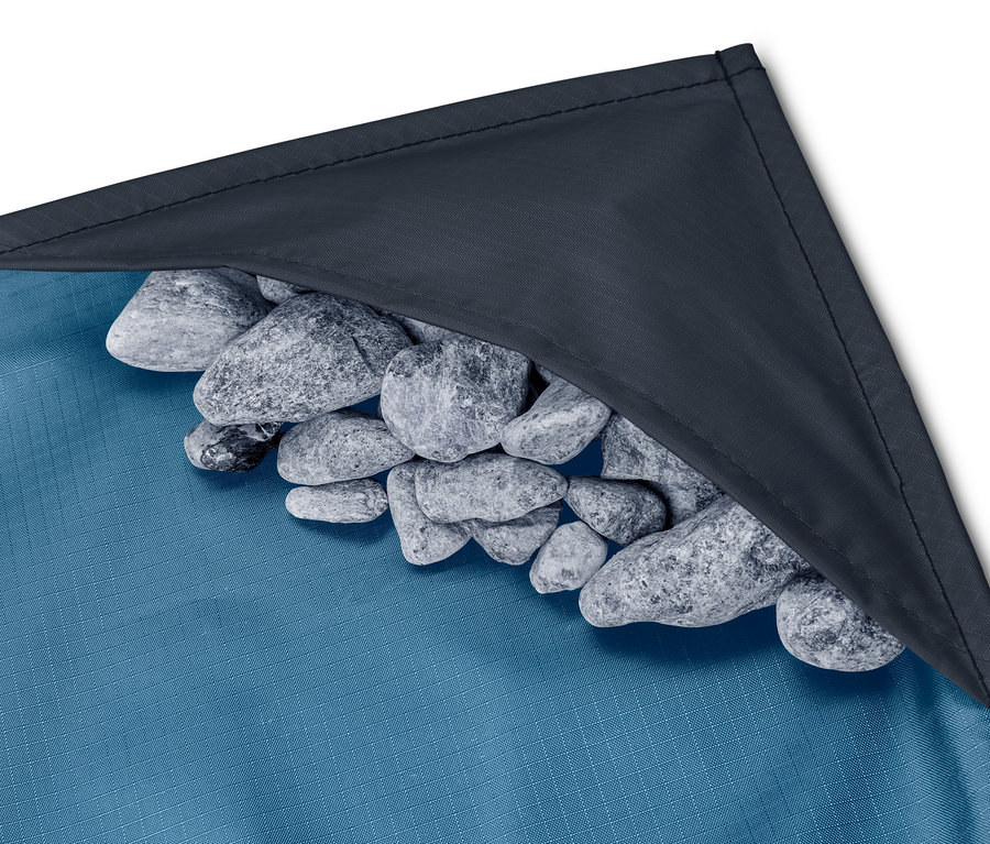 Köşesinde bir yığın taş bulunan mavi mini piknik örtüsünün yakın çekimi.