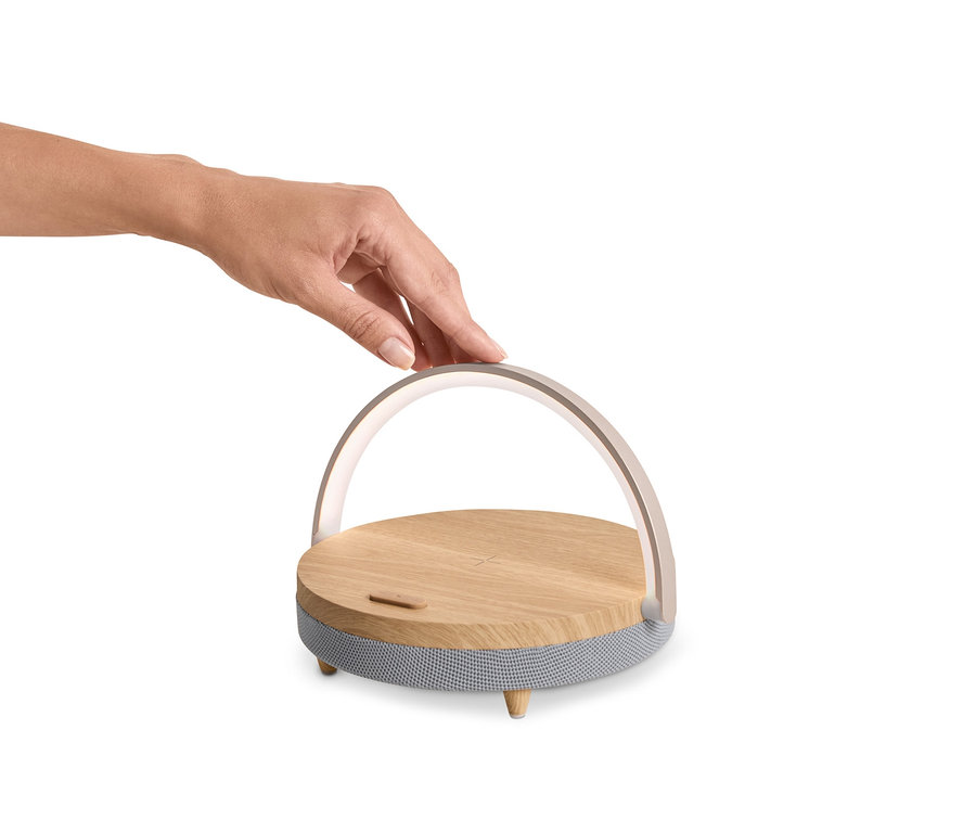 Bir el, Kablosuz Şarj Cihazlı ve LED Gece Işıklı Bluetooth Hoparlöre dokunuyor.