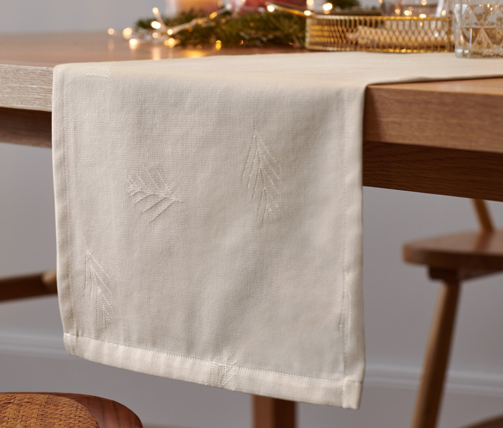 Kırık beyaz renkli jakar runner, yılbaşı dekoruyla birlikte masanın üzerinde duruyor.