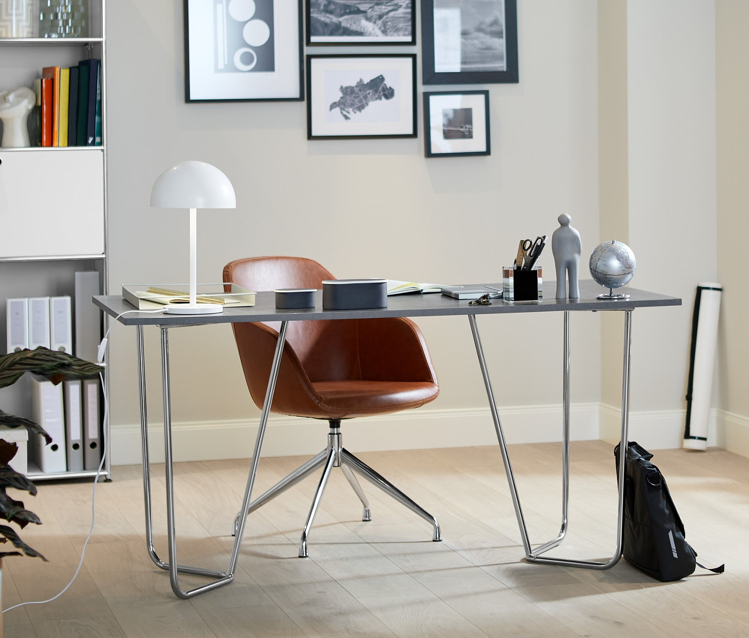 Metal iskeletli taş görünümlü tasarım masa, suni deri döşemeli döner sandalye ve LED metal masa lambası ile iç mekan. Arka planda yüksek metal raf ve metal bir konsol bulunmaktadır.