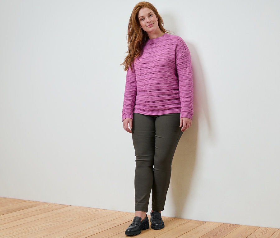 Kadın Streç Pantolon ve ajurlu desenli kazakla poz veriyor.