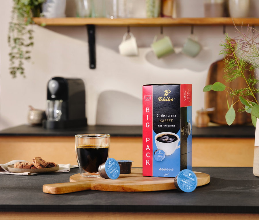Tezgahta bir bardak kahve, bir paket Cafissimo Pure+, Siyah ve iki kapsül duruyor.
