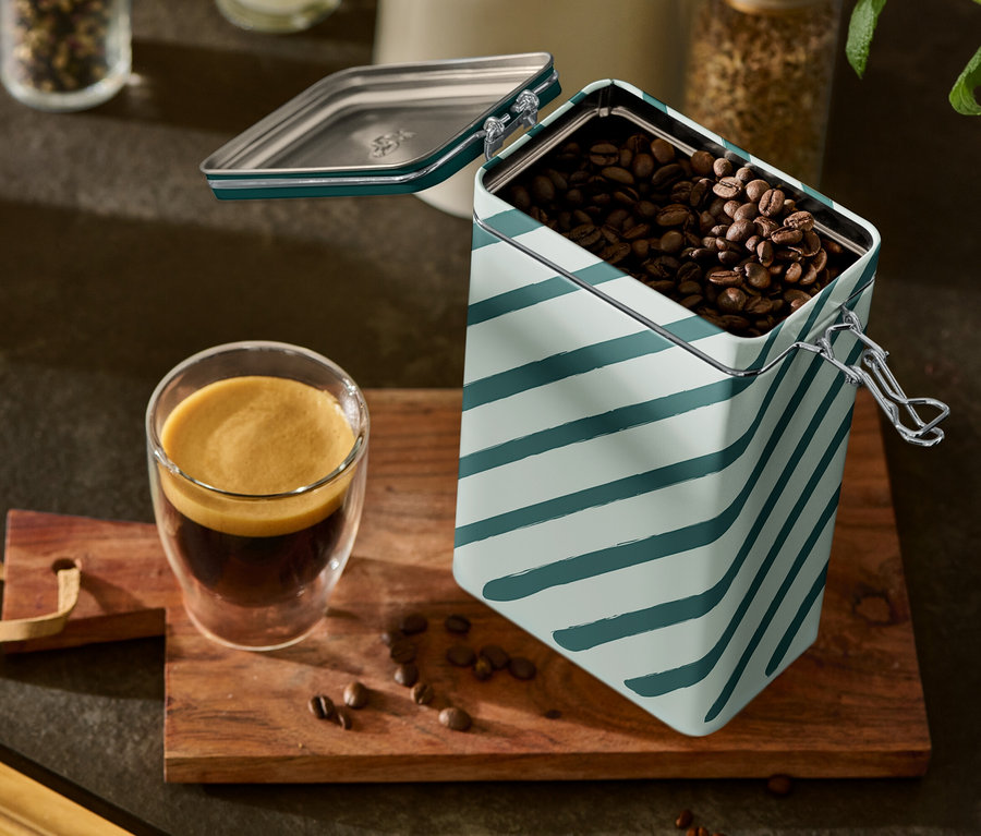 Bir bardak espresso ve açık, şeritli bir kahve kutusu ahşap bir tahta üzerinde duruyor.