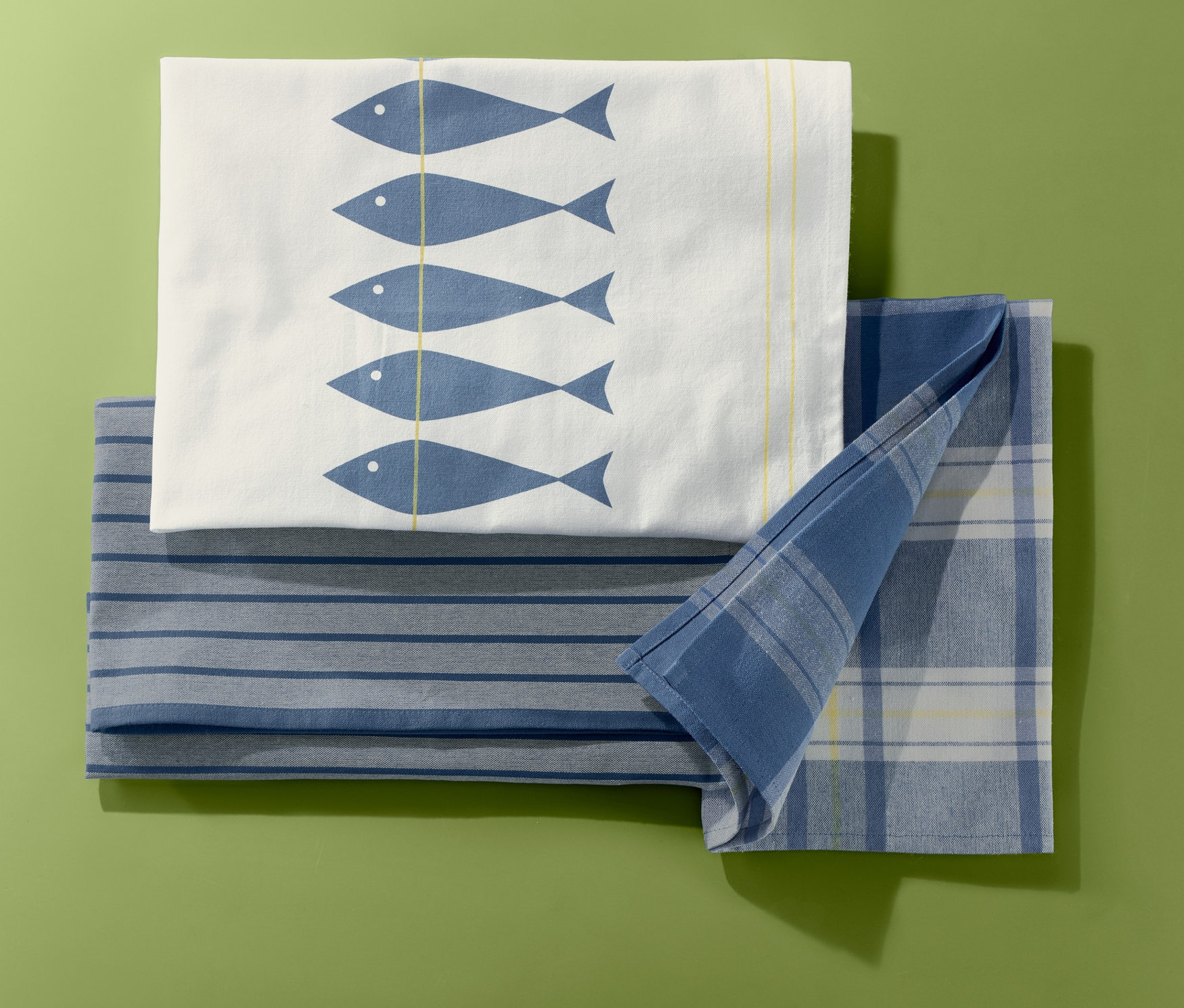 Yeşil zemin üzerinde balık, çizgi ve kare desenli üç adet bulaşık bezi.
