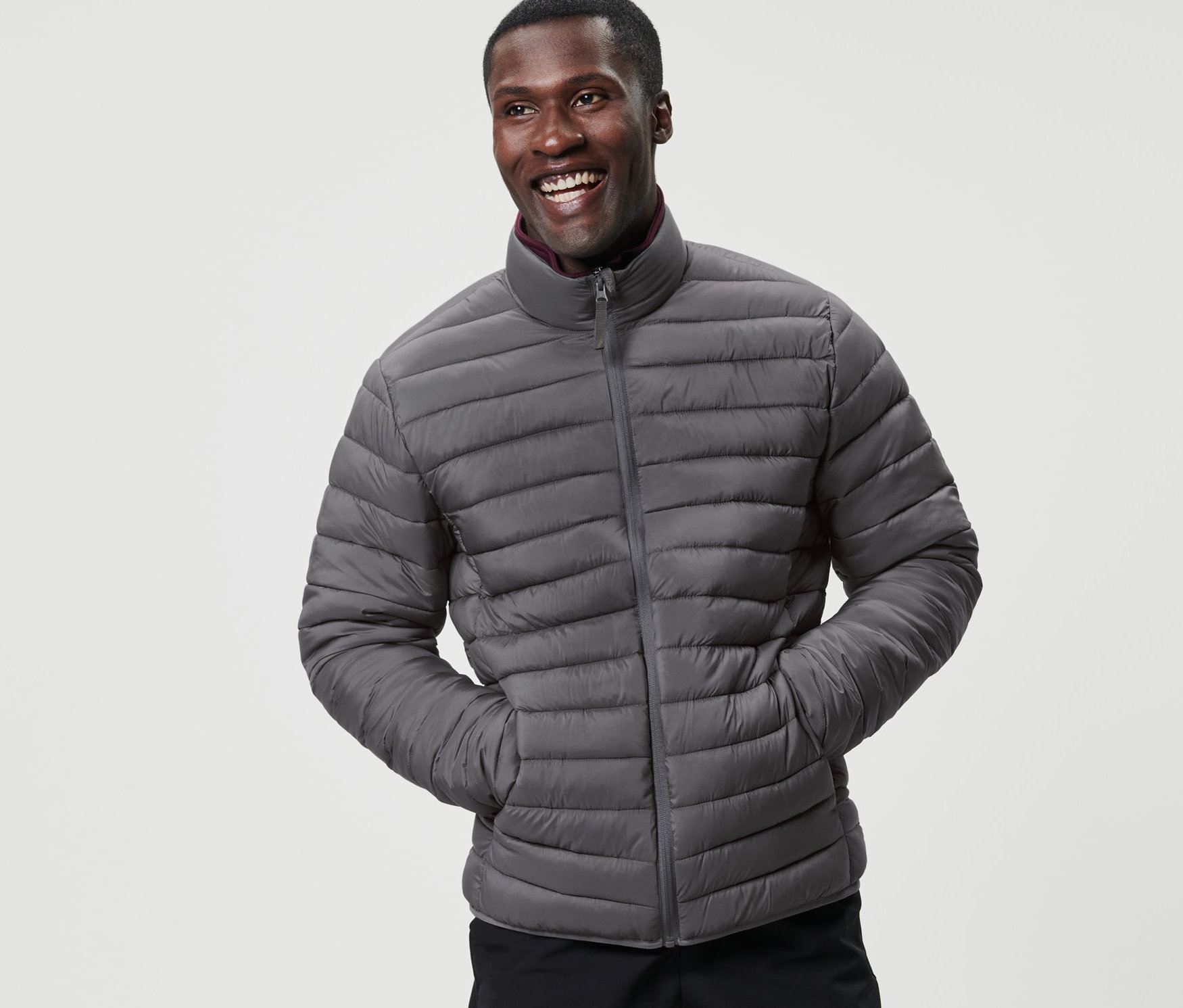 Gülümseyen bir adam katlanabilir kapitone mont ile poz veriyor.