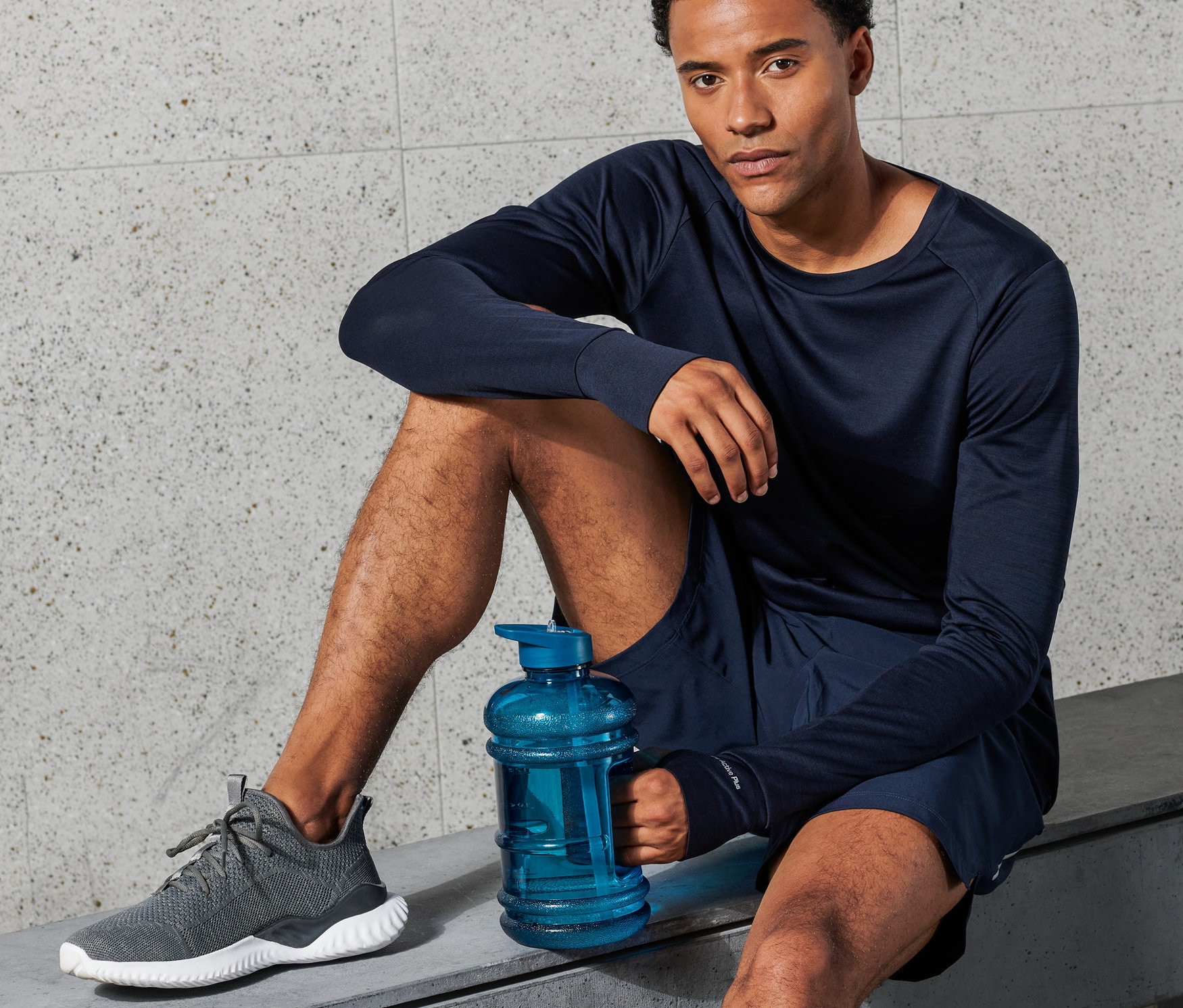 Adam bankta oturuyor ve mavi bir XXL Su Şişesi tutuyor.