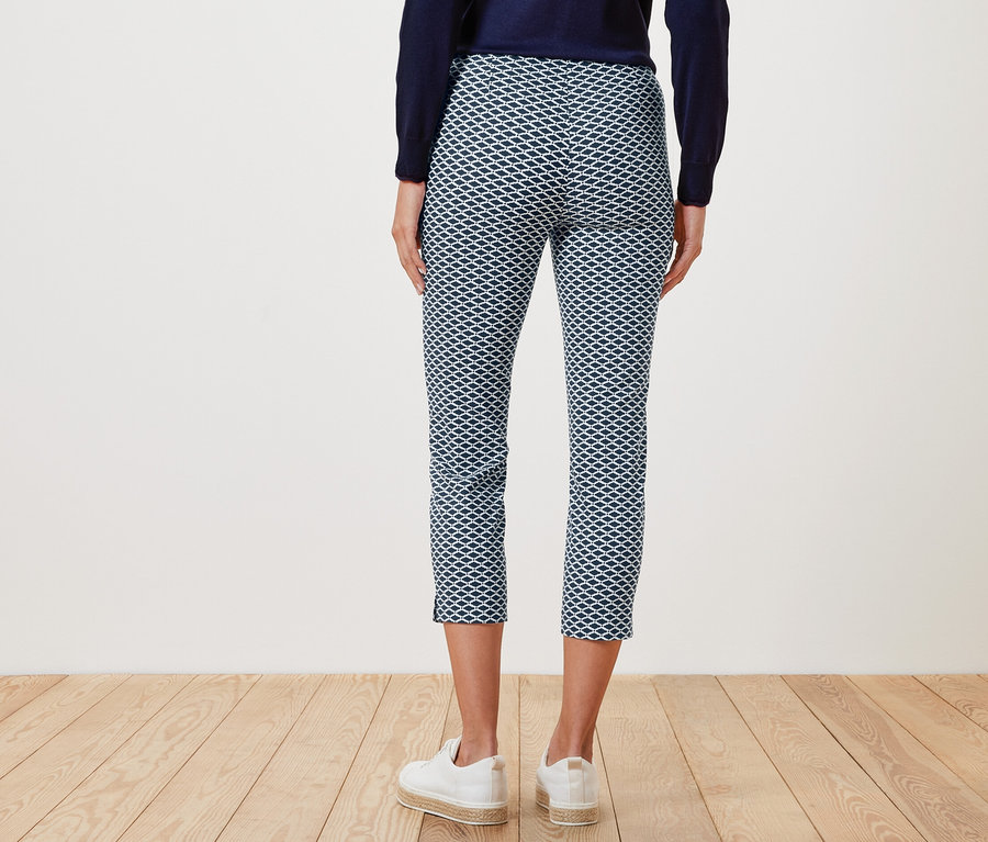 Arkadan görünüşüyle, baskılı 7/8 streç pantolon ve beyaz spor ayakkabı giyen bir kadın.