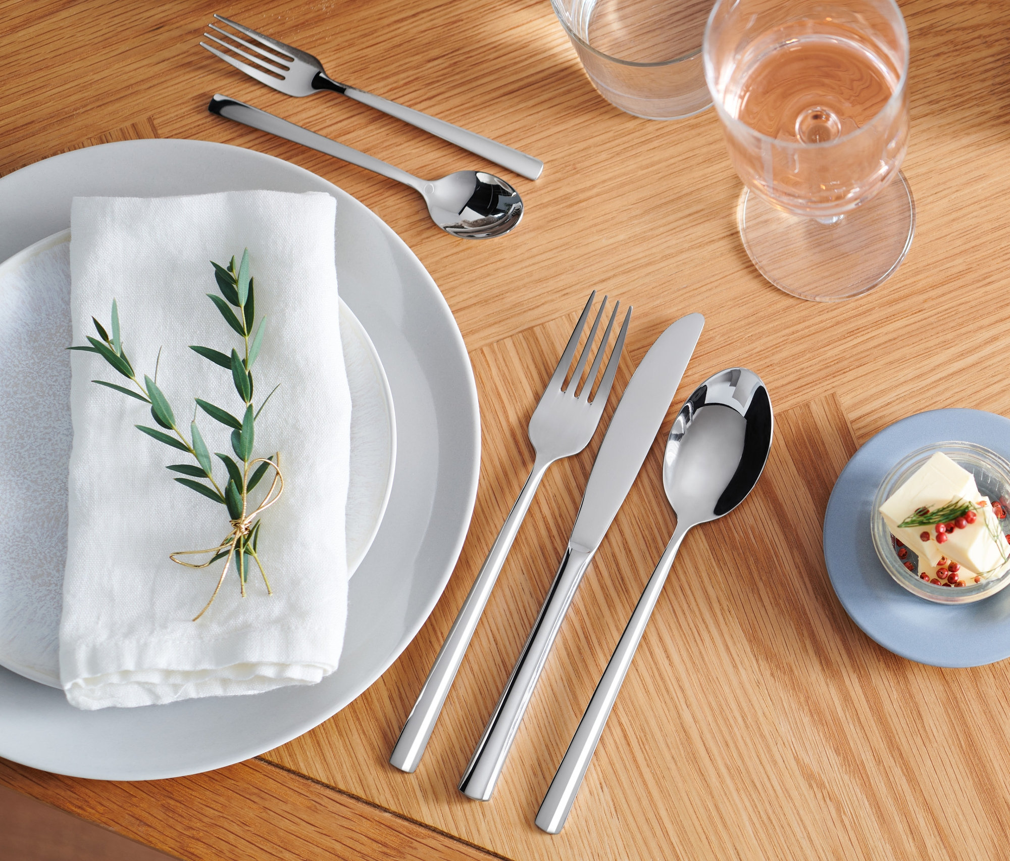 Ahşap masa üzerinde paslanmaz çelik renginde 20 parçalı çatal bıçak kaşık seti.